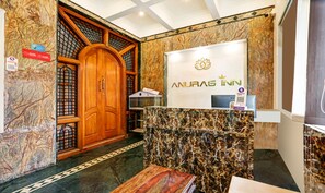 A reception desk with a marble counter and a wooden door. - Itsy Hotels Anurag Inn (Mysore)