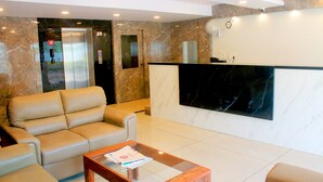 Eine moderne Lobby mit einer Rezeption, einer Couch, einem Couchtisch und einem Aufzug.