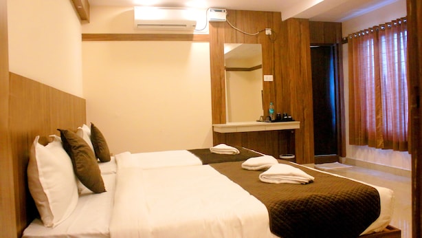 Ein Hotelzimmer mit einem großen Bett, einem Spiegel, einem Schminktisch und einem Fenster mit Vorhängen.