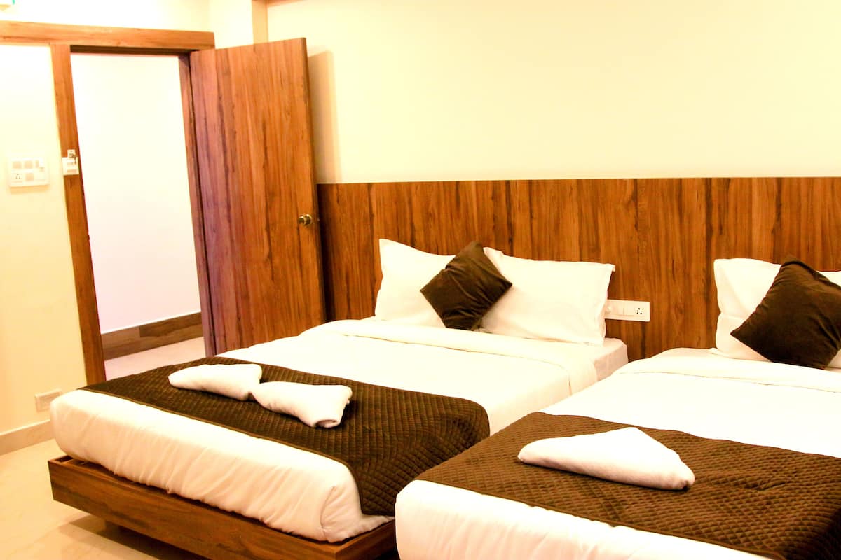 A hotel room with two beds, wooden headboards, white bedding, and a wooden door.