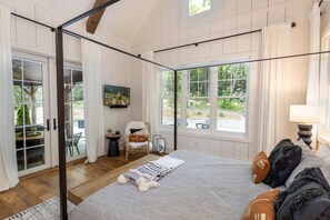 Un dormitorio con una cama grande, televisión, una silla y vistas al exterior.