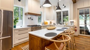 Una cocina moderna con una isla central, electrodomésticos de acero inoxidable y taburetes de madera.