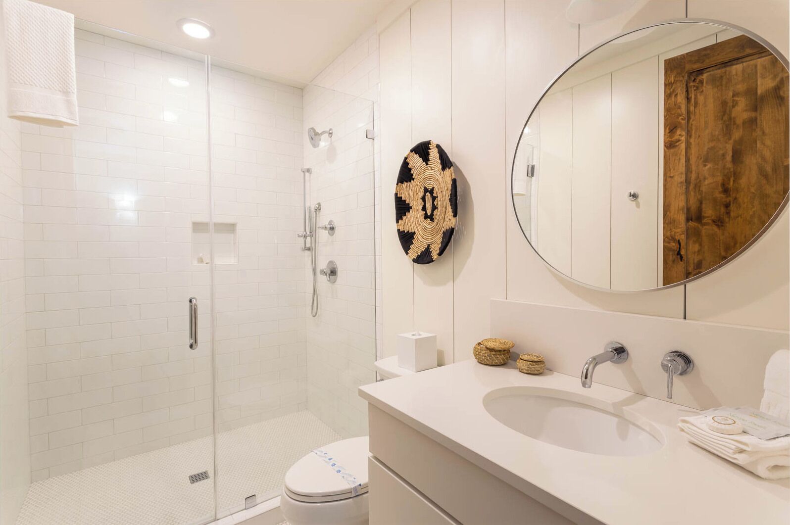 A modern bathroom with a glass-enclosed shower, a white sink, and a wooden vanity.