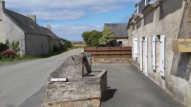A narrow street with stone buildings, a wooden fence, and a door with a mailbox.