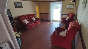 A living room with a red sofa, a television, and a sliding glass door.
