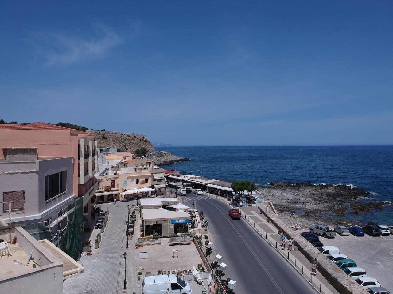 Una calle costera con edificios, una carretera y vistas al mar.