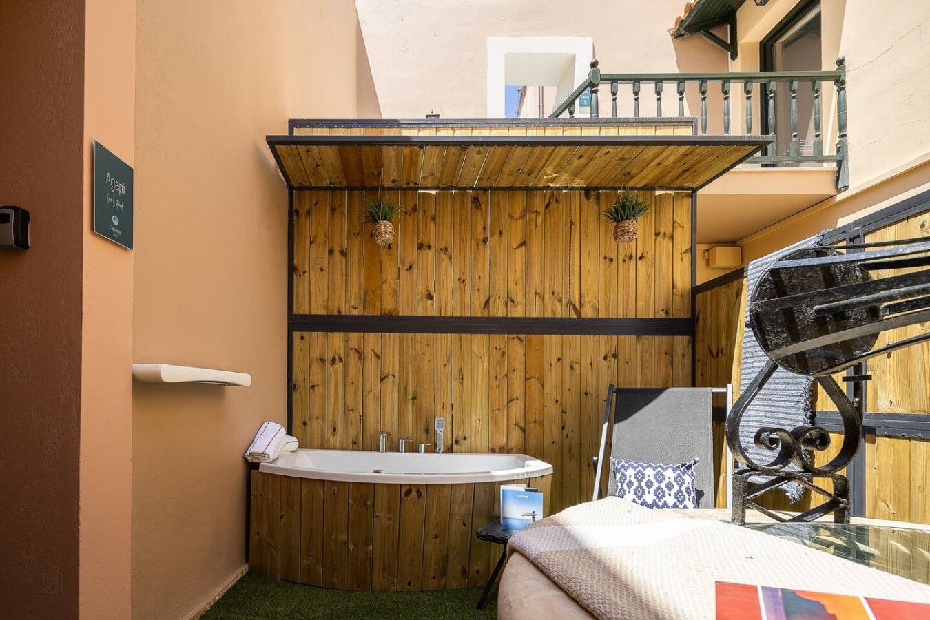 Un baño pequeño con pared de paneles de madera, una bañera independiente y una mesita con una toalla.