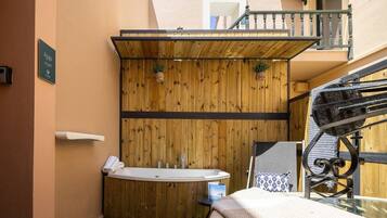 Un baño pequeño con pared de paneles de madera, una bañera independiente y una mesita con una toalla.