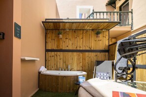 Un baño pequeño con pared de paneles de madera, una bañera independiente y una mesita con una toalla.