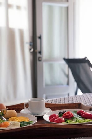 A breakfast tray with eggs, toast, and vegetables on a wooden table, a white cup, and a chair in the background. - Agapi Suite Accessible Luxurious Accommodat. Jacuz (Ρέθυμνο)