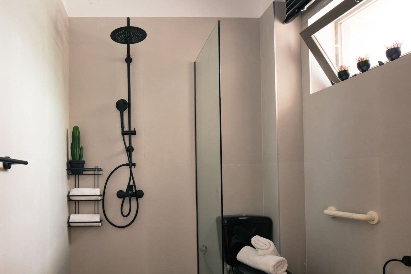 A modern bathroom with a glass shower enclosure, a toilet, and a towel rack.
