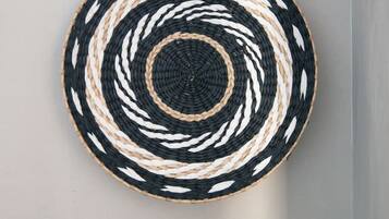 Un tapiz circular tejido con un diseño blanco y negro, un grifo negro y un taburete de madera.