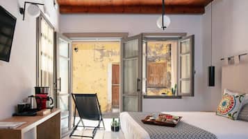 A bedroom with a bed, a desk, a chair, and a view of the outside.