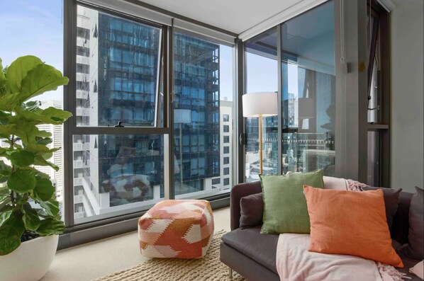 Relax in this stylish living room with a city view, featuring a sofa, ottoman, and floor lamp.