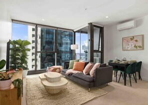 Relax in this stylish living space with a city view, featuring a sofa, coffee table, and dining area for two.