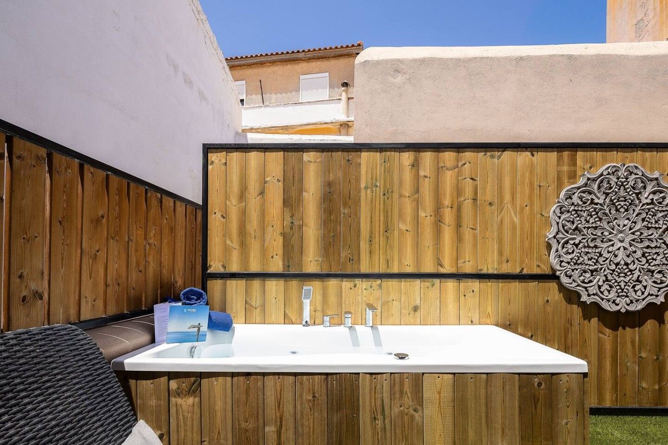 A wooden fence with a white sink and a decorative wall piece.