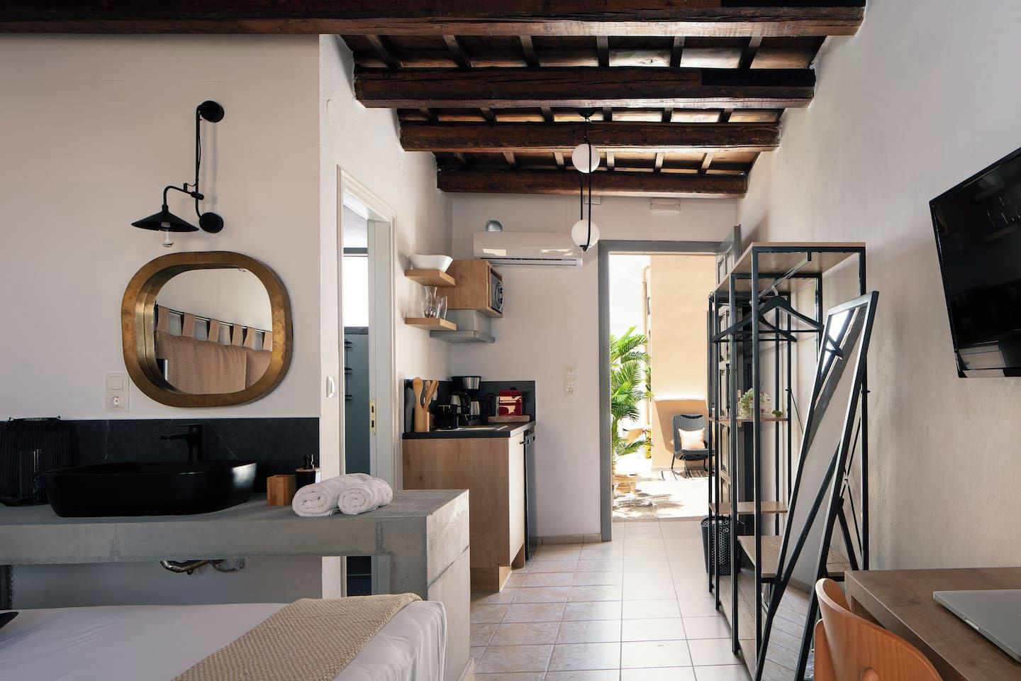 A modern kitchen with a built-in oven, a dining area with a table and chairs, and a large mirror above the sink.