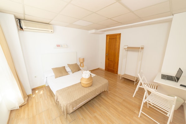 A bedroom with a bed, bedside table, lamp, and a desk with a laptop. - Old Town La Estacion (Alicante)