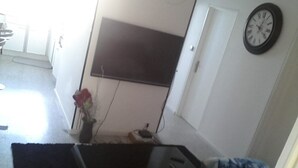 Une pièce comprenant un lit, une table de chevet, une horloge murale et une porte.