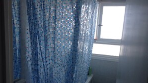 Une salle de bain avec une baignoire, une fenêtre et un rideau de douche.