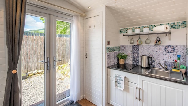 Una cocina con encimera negra, armarios blancos y salpicadero de azulejos.
