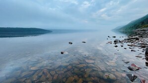 Ein klarer See mit sichtbaren Felsen und einer felsigen Uferlinie.