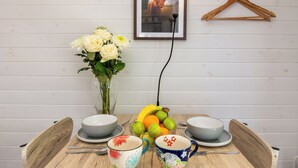 Una mesa de comedor con un florero, fuentes y un frutero.