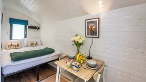 Una habitación acogedora con una cama, una mesita con un jarrón de flores y un cuadro en la pared.