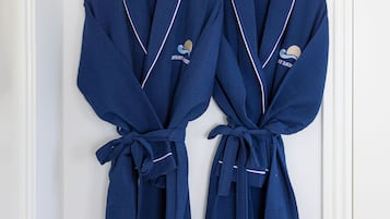 Dos túnicas azules colgadas en una puerta blanca con un estante blanco encima.