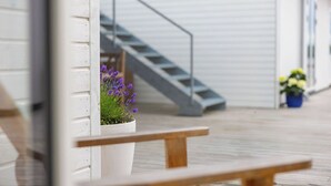 A wooden bench, a white planter with purple flowers, a grey staircase, and a building with a white exterior. - Hørby Færgekro (Holbaek)