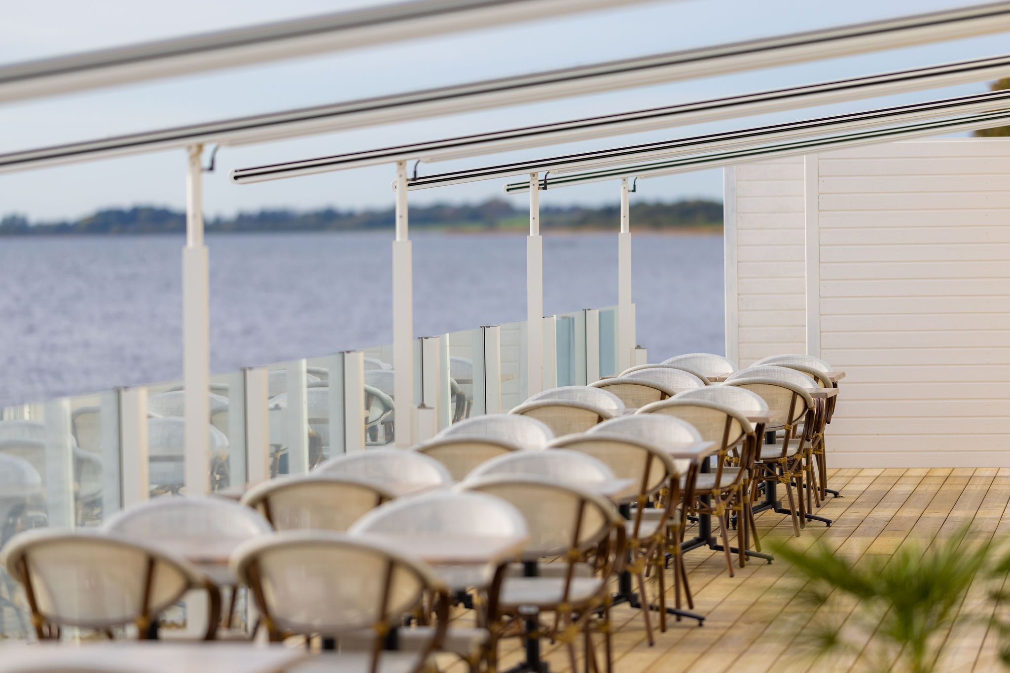Une rangée de chaises sur une terrasse extérieure, avec vue sur l’eau.