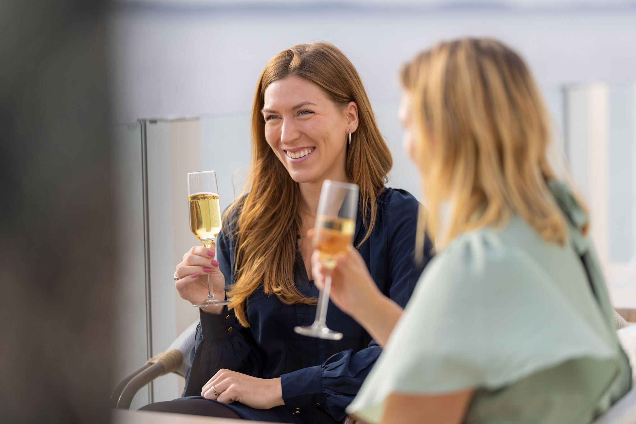 Zwei Personen sitzen an einem Tisch und trinken jeweils ein Glas Wein.