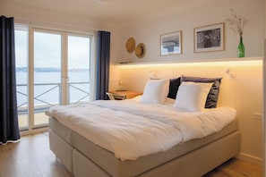 A hotel room with a bed, a desk, a chair, a view through a glass door, and wall decorations.