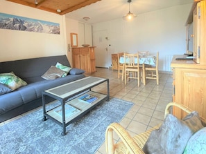 Uma sala de estar com sofá, mesa de centro e área de jantar com cadeiras e mesa.