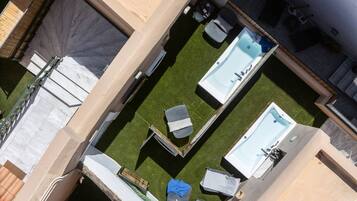Una terraza en la azotea con piscina, zona de estar y un pequeño jardín.
