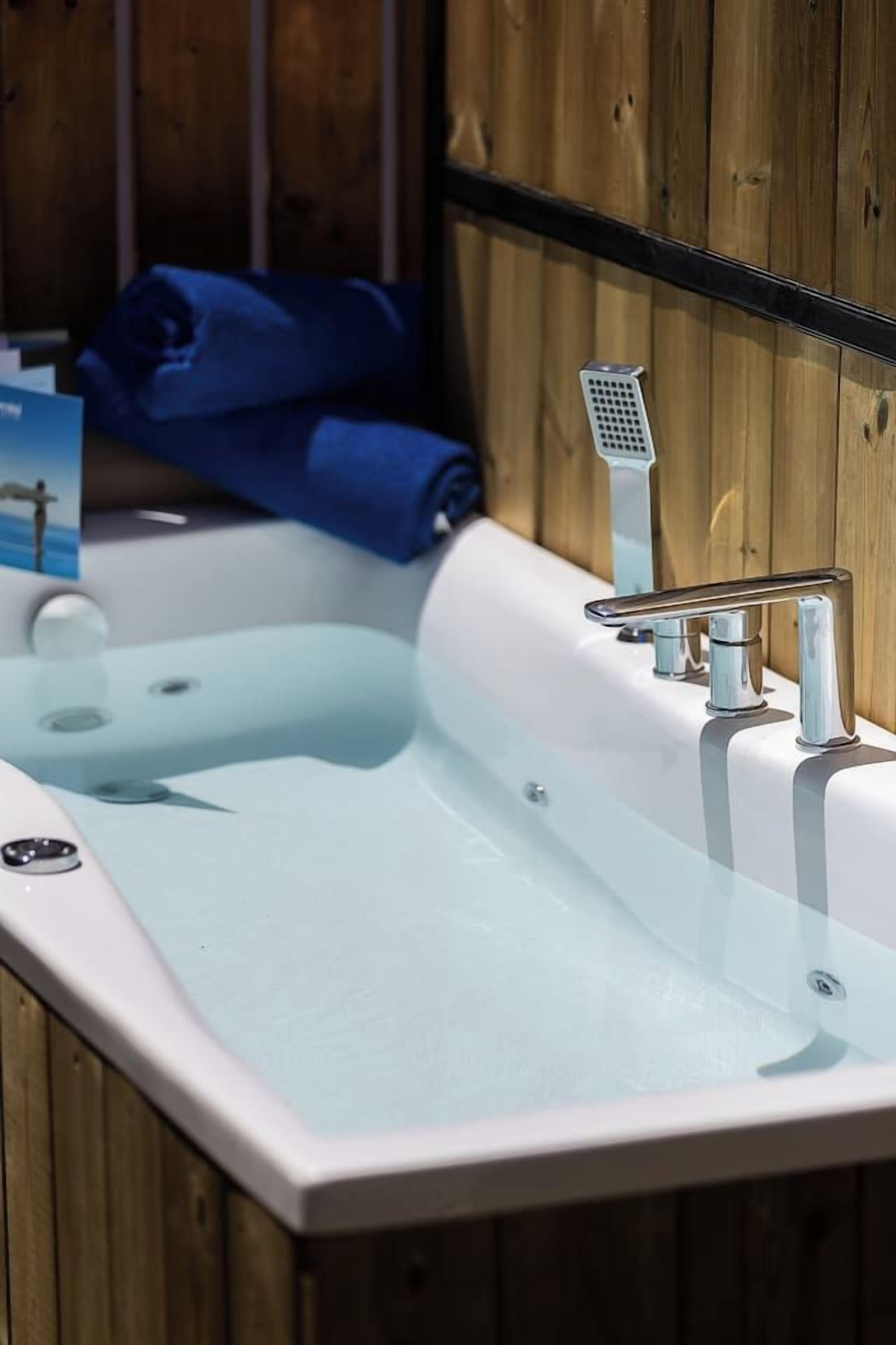 Un baño moderno con bañera vidriada, accesorios cromados y paneles de madera.