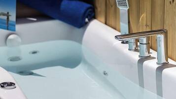 Un baño moderno con bañera vidriada, accesorios cromados y paneles de madera.