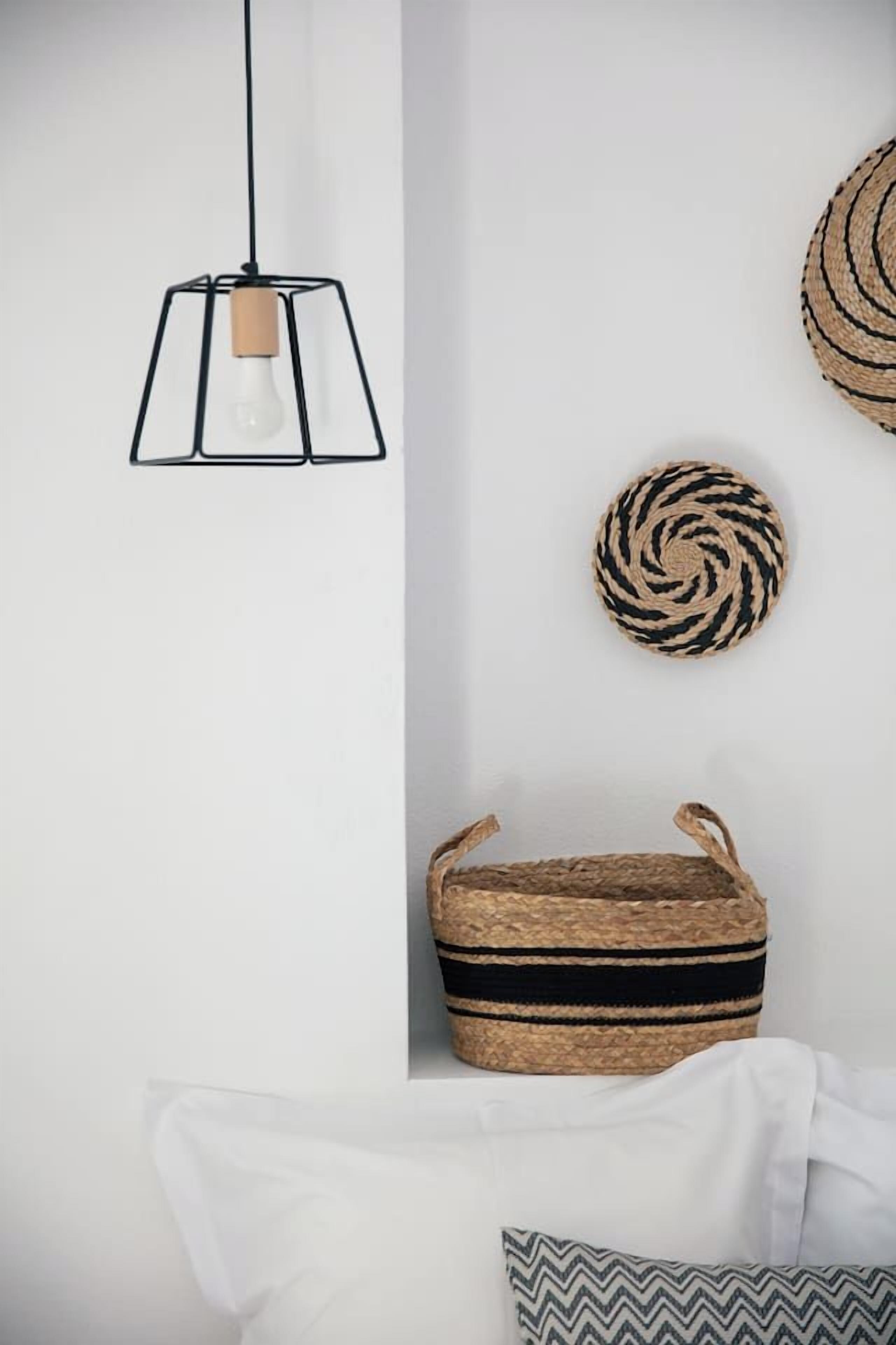 A room with a hanging light fixture, a woven basket, and a circular woven item on the wall.