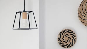 Una habitación con una lámpara colgante, una cesta tejida y un objeto circular tejido en la pared.