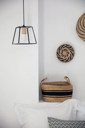 A room with a hanging light fixture, a woven basket, and a circular woven item on the wall. - Gateway Suites - Pathos (Ρέθυμνο)