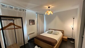 A bedroom with a wooden bed, a hanging wardrobe, a fluffy rug, and a bedside lamp. - Superb modern T3, 5 minutes from the Old Port (Marseille)