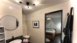 A modern bathroom with a round mirror, white sink, and black countertop. There is a toilet and a framed picture on the wall. - Superb modern T3, 5 minutes from the Old Port (Marseille)