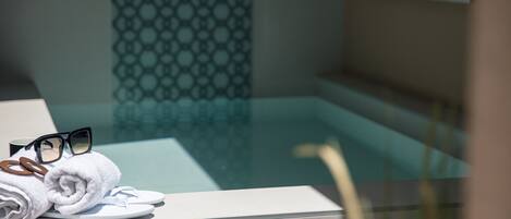 Un baño con piscina envasada en vidrio, una toalla y un par de gafas sobre una encimera.