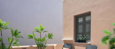 A balcony with two wicker chairs, a small table, and potted plants.