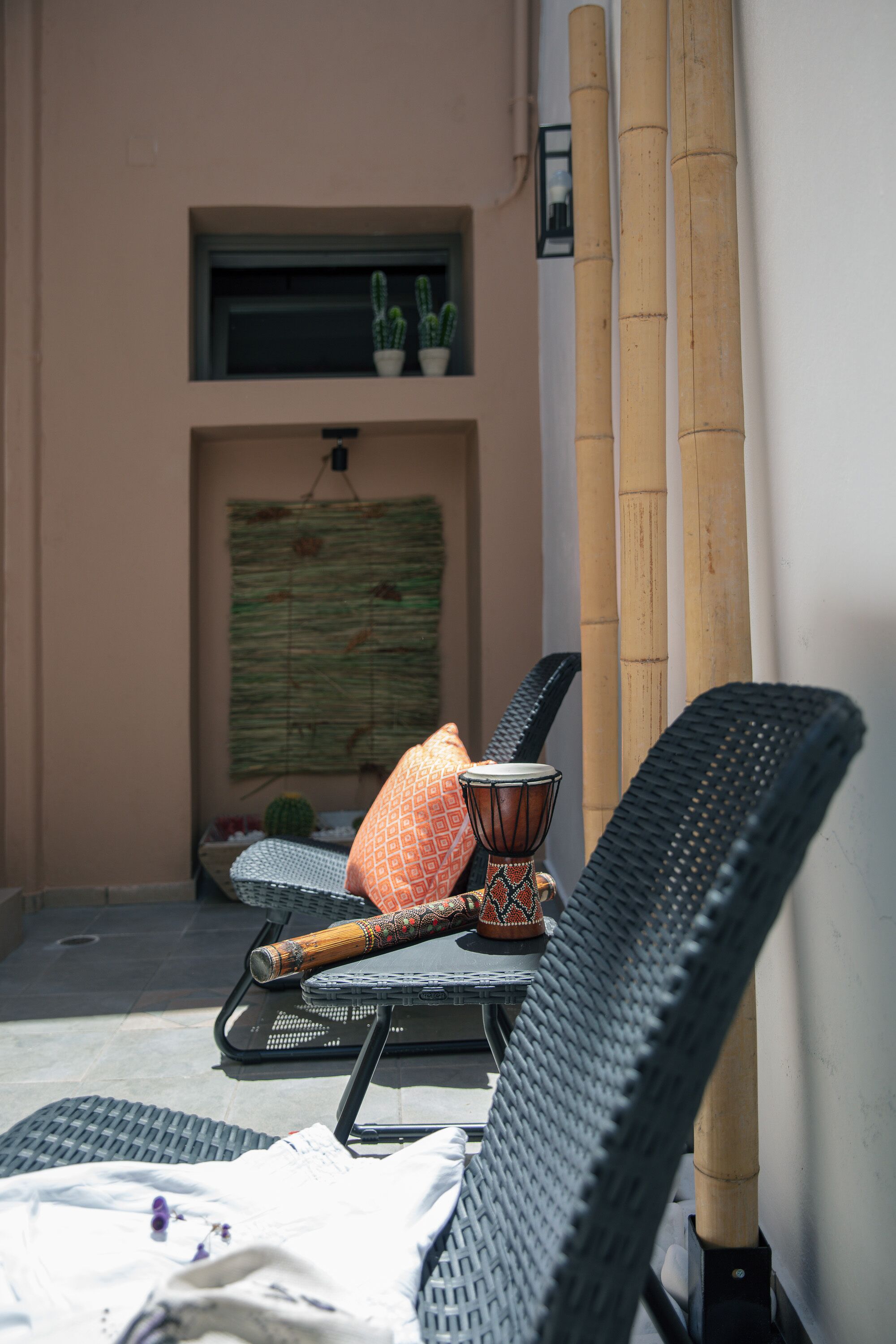 A seating area with wicker chairs, a patterned cushion, and a decorative pot.