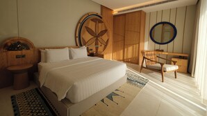 Een moderne hotelkamer met een groot bed, een houten hoofdeinde, een ronde spiegel, een houten bureau en een stoel.
