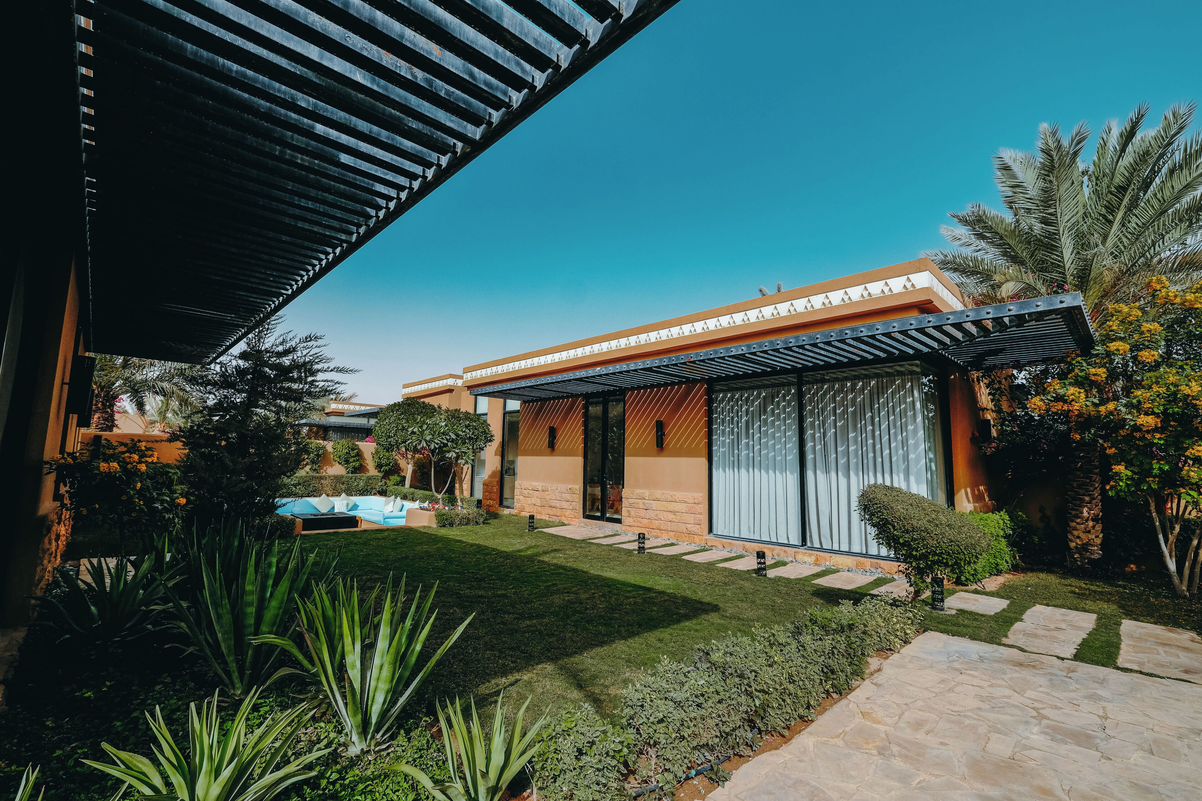 A modern house with a well-maintained lawn, a swimming pool, and a pergola.