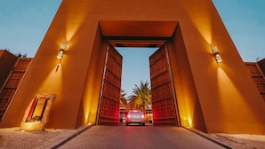 Een auto rijdt door een brede, open boog met verlichte muren, die leidt naar een gebouw met een modern ontwerp.