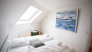 A bedroom with a bed, skylight, and a painting of a ship on the wall. - Harbour View - Marina - City Centre (Tórshavn)