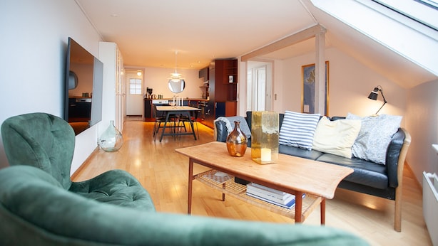 A modern living room with a sofa, a coffee table, and a dining area in the background. - Harbour View - Marina - City Centre (Tórshavn)